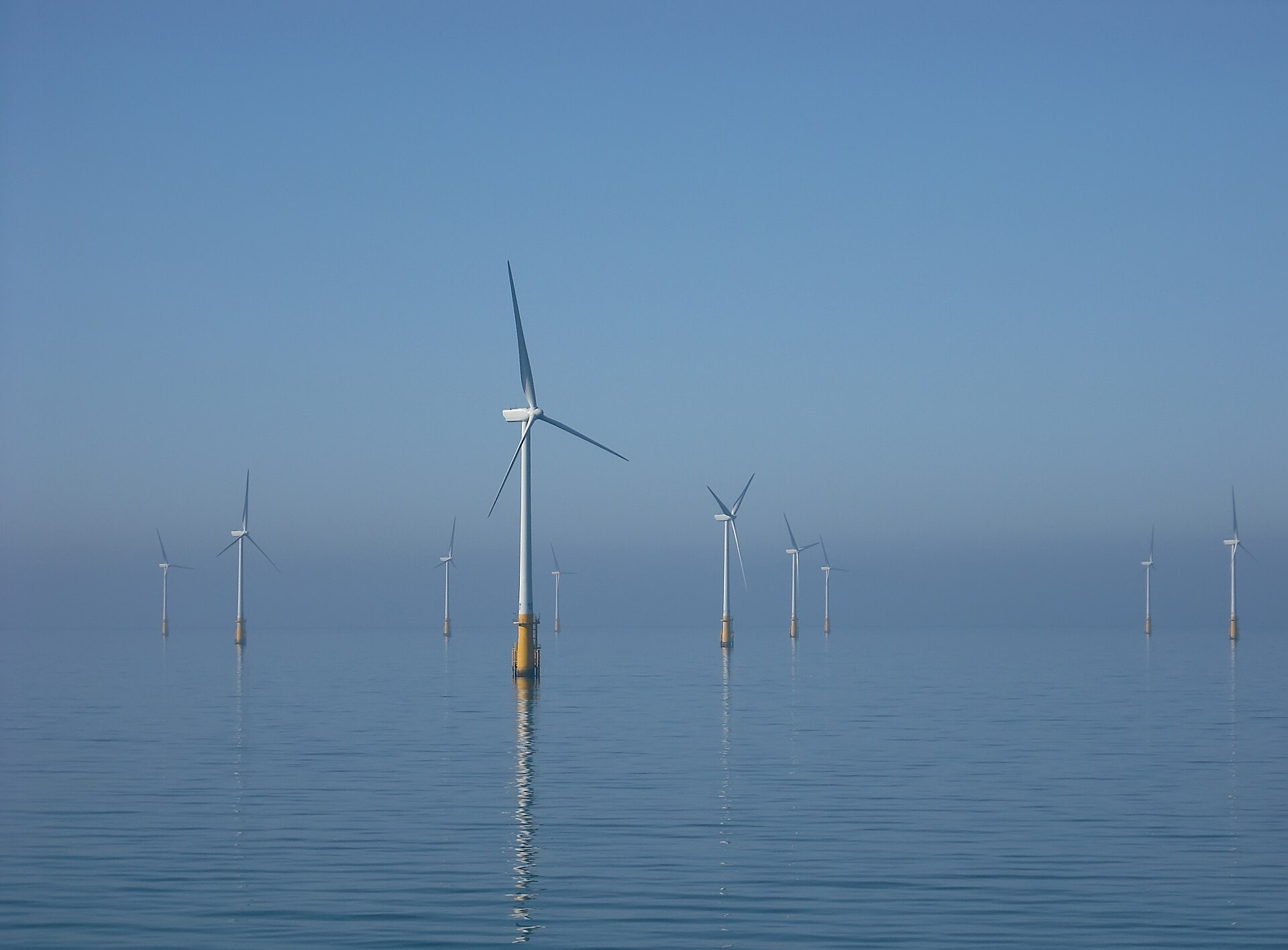 Offshore wind turbines reflected in calm sea water